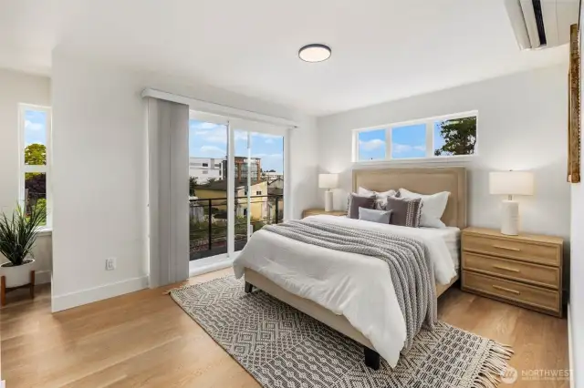 Large windows and a private balcony fill the primary bedroom with light and fresh air.