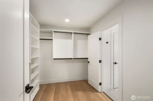Spacious and well-lit walk-in closet with custom shelving and double hanging rods for optimal storage.