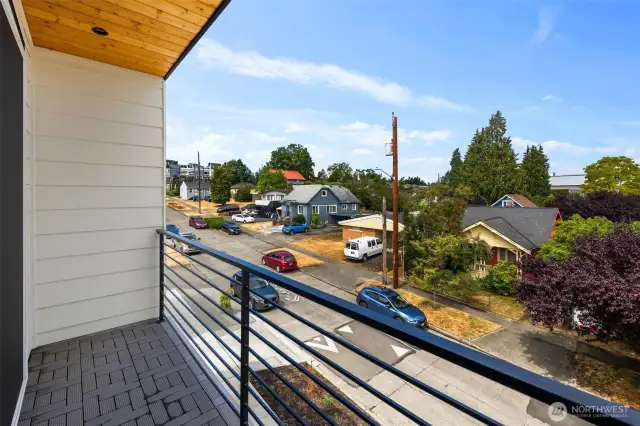 Balcony views over the charming neighborhood, with treetops and nearby vintage Seattle style homes creating a picturesque and inviting setting.