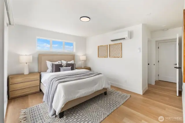 The primary suite features warm hardwood floors, clerestory windows that invite daylight, and a modern mini-split for personalized comfort.