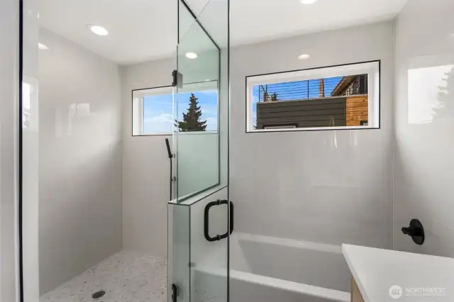 The walk-in shower feels open and comfortable, giving you space to move without feeling crowded. The deep soaking tub invites you to fully stretch out, with sunlight from the nearby window creating a relaxing, spa-like atmosphere.