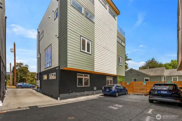 A wide driveway entry leads to a spacious parking area, offering easy access in and out from the street.