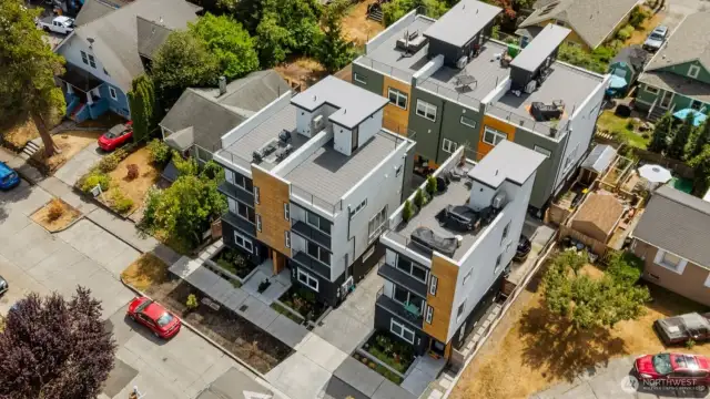 An aerial view highlights the townhouse’s modern architecture, private rooftop decks, and prime corner location, set among a charming mix of established homes in this tree-lined neighborhood.