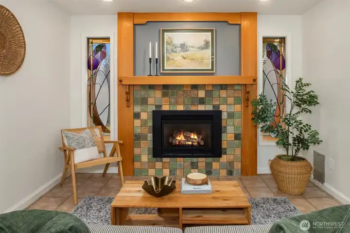 The craftsman gas fireplace is flanked by custom stained glass windows, created by the former owner who is a stained glass artist. Pieces of his art can be seen throughout the home.