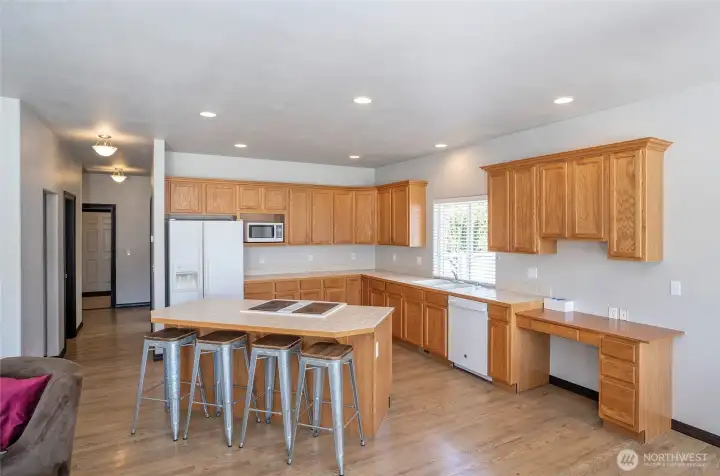 Island kitchen with seating at the island and a convenient built-in desk area, offering both style and functionality, plus extensive cabinetry for excellent kitchen storage.