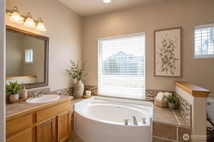 Primary ensuite featuring a soaking tub with a relaxing view - virtually staged.