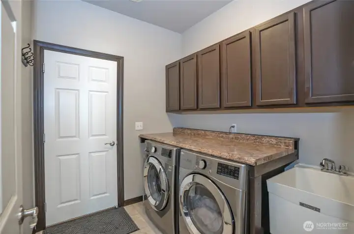 Utility room featuring generous counter space, a utility sink, and additional cabinetry for extra storage.