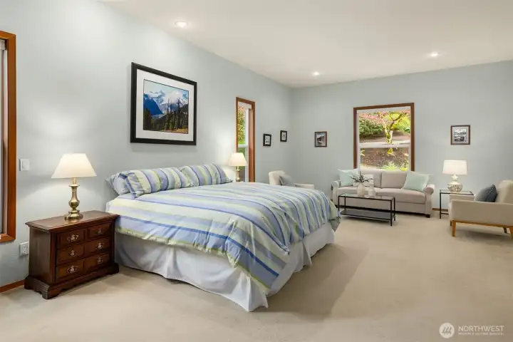 The primary suite has room for a sitting ares and has windows overlooking the gorgeous property.