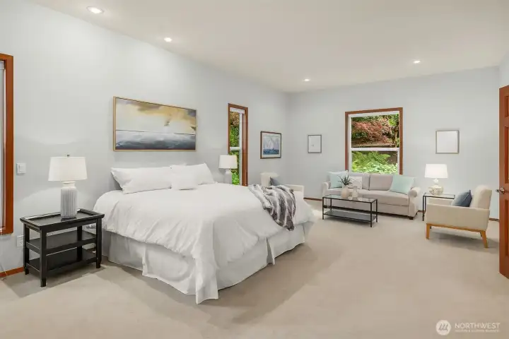 The primary suite has room for a sitting area and has windows overlooking the gorgeous property.