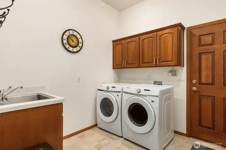Large laundry room with laundry sink and cabinetry