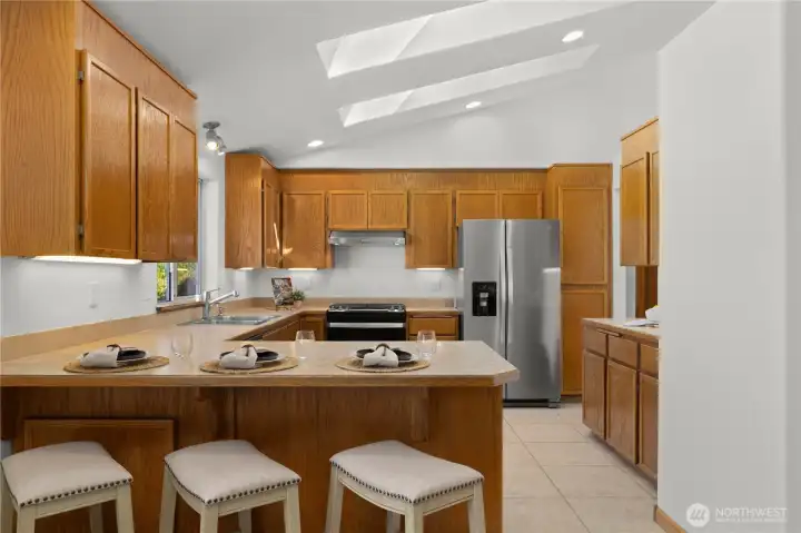 Open kitchen with stainless steel appliances, undermount lighting, and skylights flooding the space with natural light. Open kitchen with stainless steel appliances, undermount lighting, and skylights flooding the space with natural light.