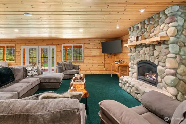 Cozy seating in front of living room fireplace w/French door access to back deck and corner TV viewing