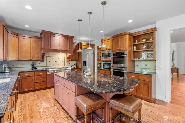 Chef’s kitchen with oversized granite island, double ovens & gas cooktop.