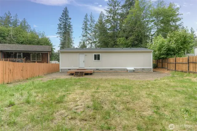 Second view from rear of home showcasing the large level backyard.