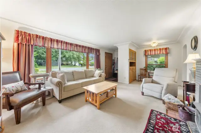Bright and cozy living room featuring large windows and a comfortable layout.  Hardwood floors under well-cared carpet.