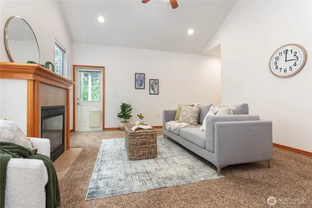 Living room w/ vaulted ceilings and door to private deck