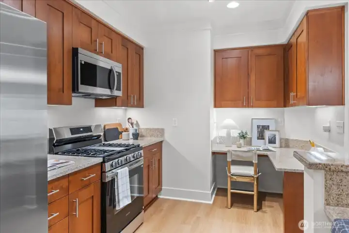 Step-saving kitchen features granite counter, Shaker style cherry stained cabinetry with underlighting and handy desk alcove for computer work . . .