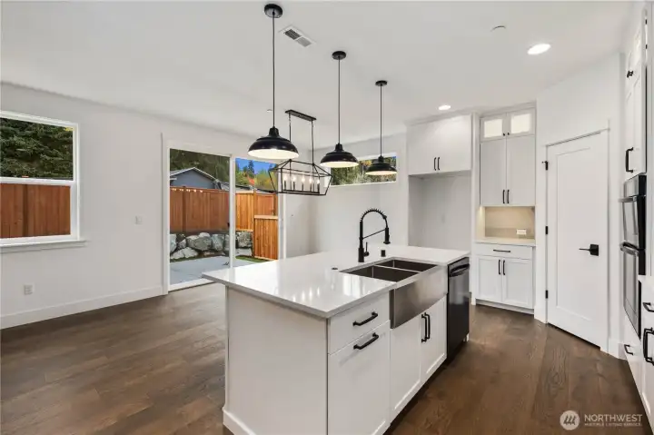 Kitchen:  This bright kitchen features white cabinetry, quartz countertops, a statement island with a farmhouse sink, and oversized pendant lighting that adds depth and visual balance. Its open layout supports cooking, gathering, and effortless movement between the main living areas. Positioned in Bothell’s Canyon Park neighborhood, the space benefits from proximity to local shopping, parks, and commuter routes, making daily routines streamlined and connected. Modern finishes, warm wood flooring, and thoughtful storage create a kitchen designed for both everyday ease and elevated hosting.    These photos are from Lot 5 at Gooden Hollow, the home listed here. However, other homes in the community will have changes, so all photos, renderings, site maps, and floorplans are for visualization purposes only. Plans, colors, building orientation, finishes, home outlook, and other details can and WILL vary.