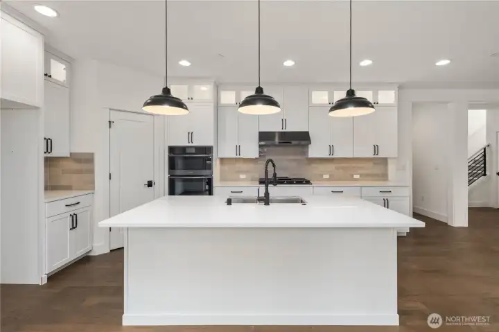 Kitchen Island:  A generous quartz island sits at the center of the kitchen, paired with matte black pendants that give the space a bold, contemporary feel. The island’s size and layout provide room for prep work, serving, or casual seating, all while keeping the cook connected to the rest of the main floor. With its location in Bothell’s sought-after Canyon Park corridor, daily errands, dining options, and Northshore schools are all close at hand. This island becomes a natural gathering point, blending function and design for effortless Northwest living.    These photos are from Lot 5 at Gooden Hollow, the home listed here. However, other homes in the community will have changes, so all photos, renderings, site maps, and floorplans are for visualization purposes only. Plans, colors, building orientation, finishes, home outlook, and other details can and WILL vary.
