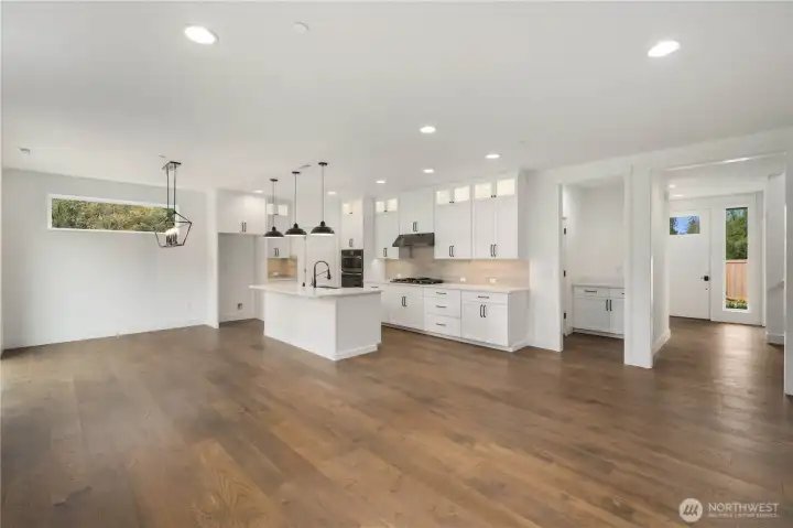 Main Living Overview:  Wide sightlines connect the kitchen, dining area, and great room, emphasizing natural light from multiple windows and the warm tones of the engineered hardwoods. This open-concept layout offers exceptional flexibility for furniture placement and comfortable living. Located in Bothell’s Canyon Park area, the home provides quick access to shopping, Northshore schools, and major commuting routes, making day-to-day life both convenient and connected. The scale of the space lends itself beautifully to hosting, creating room for gatherings of all types while maintaining a clean, modern aesthetic.    These photos are from Lot 5 at Gooden Hollow, the home listed here. However, other homes in the community will have changes, so all photos, renderings, site maps, and floorplans are for visualization purposes only. Plans, colors, building orientation, finishes, home outlook, and other details can and WILL vary.