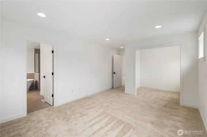 Primary Suite – Expanded View:  This wider perspective highlights the suite’s spacious layout, recessed lighting, and direct connection to the spa-inspired bath and attached sitting room. Its thoughtful floorplan promotes easy flow between rest, dressing, and relaxation areas. Being part of the Canyon Park community in Bothell means the suite sits moments from everyday conveniences, Northshore schools, and outdoor recreation. The overall scale invites a sense of calm and allows you to shape the space to match your preferred style of retreat.    These photos are from Lot 5 at Gooden Hollow, the home listed here. However, other homes in the community will have changes, so all photos, renderings, site maps, and floorplans are for visualization purposes only. Plans, colors, building orientation, finishes, home outlook, and other details can and WILL vary.