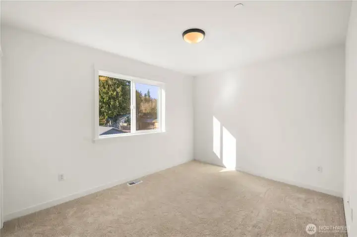 Secondary Bedroom (Rear-Facing):  This peaceful upper-level bedroom offers a serene treetop outlook framed by a wide window, along with plush carpeting and crisp white walls that keep the space feeling airy and open. Its balanced proportions make it versatile for a range of uses, with plenty of room to arrange furnishings comfortably. With the home situated near Bothell’s wooded greenbelts and nearby Northshore trails, the setting brings a quiet Pacific Northwest backdrop into everyday living. Its understated finishes create a calming environment that supports both productivity and relaxation.    These photos are from Lot 5 at Gooden Hollow, the home listed here. However, other homes in the community will have changes, so all photos, renderings, site maps, and floorplans are for visualization purposes only. Plans, colors, building orientation, finishes, home outlook, and other details can and WILL vary.