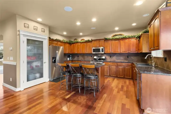 Spacious kitchen featuring generous cabinet storage, granite counters, pantry, and island seating.