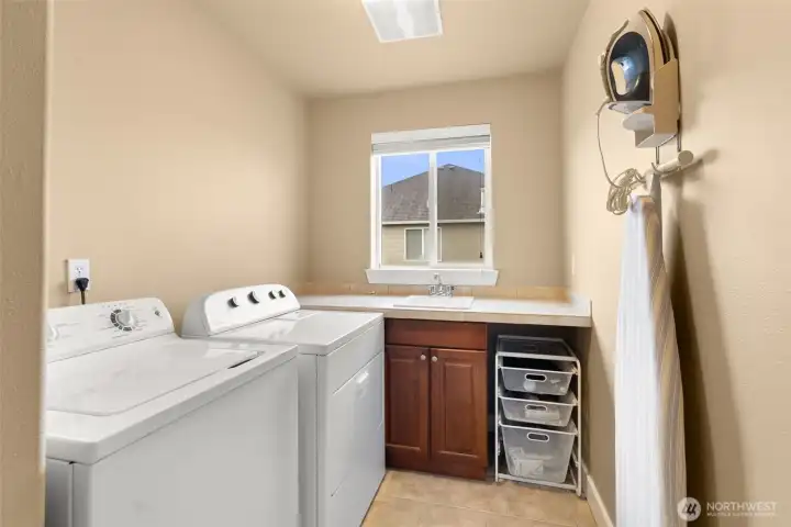 Large laundry room with tile finishes and utility sink, ideally positioned upstairs by the bedrooms.