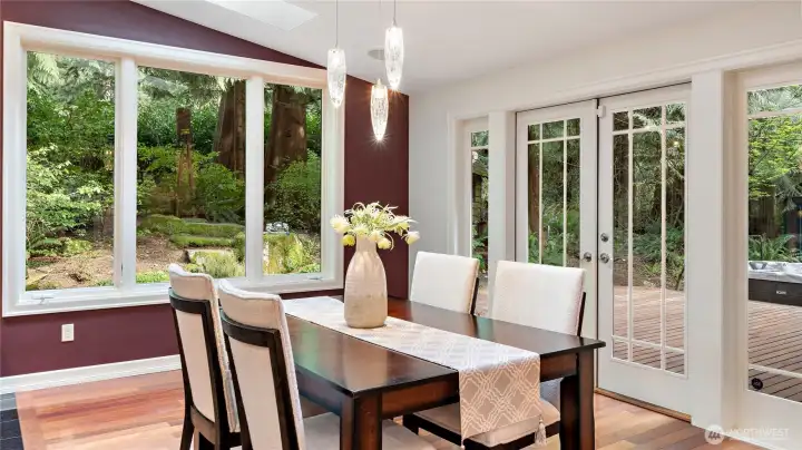 From here, the connection to the outdoors becomes even more apparent, with French doors on both sides of the room and picture windows that keep the forest close all year long. And just beyond, the deck spans the back of the home, inviting you out to take in the peaceful, wooded setting. Let's go take a look.