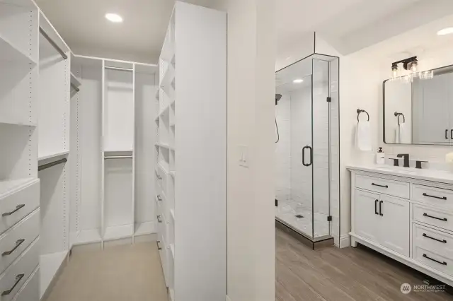 The bright remodeled spa-inspired en-suite bath features a dual vanity with Quartz counters, subway tile, frameless glass panel shower, heated floors, new lighting, and a large walk-in closet with built-in closet organizer