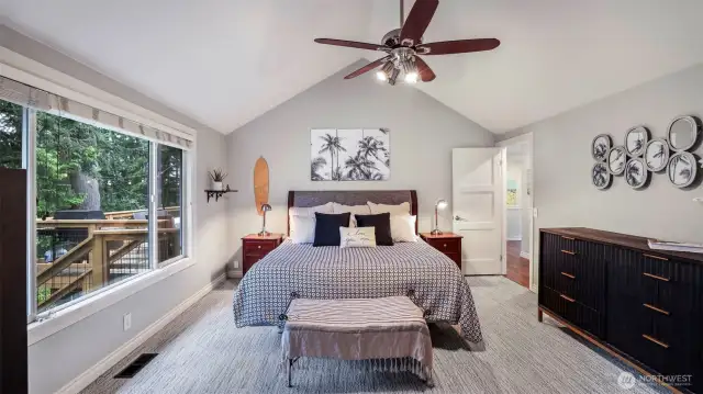 Primary suite located on the main level with vaulted ceiling, ceiling fan, walk-in closet, and en suite.