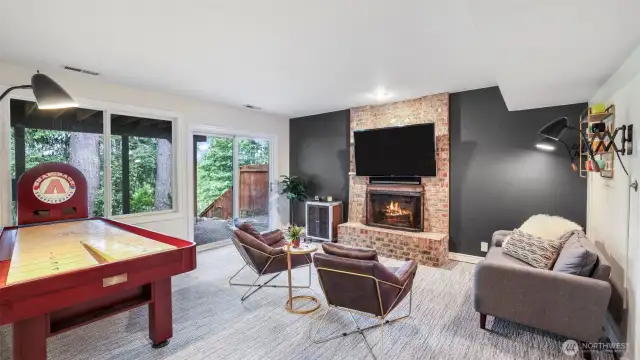 Lower level recreation room features a brick surround wood burning fireplace and hearth