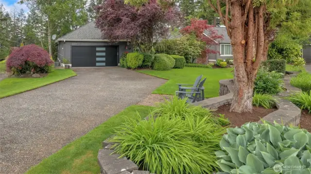 Extended driveway, lush landscaping, and new glass paneled garage door provide a welcoming and modern appeal