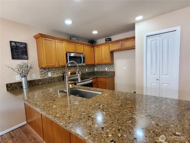 Modern kitchen shines with stainless steep appliances, sparking countertops, backslpash, pantry and eating bar.