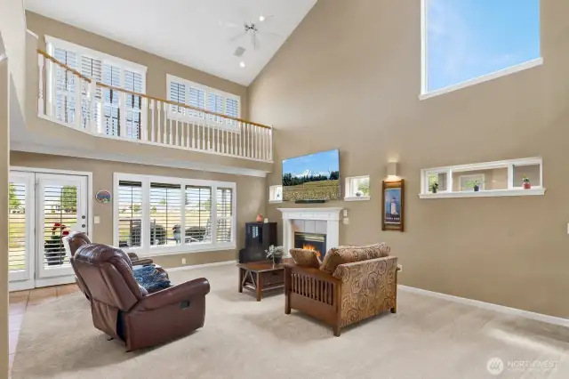 Large windows frame serene pond views, while a gas fireplace creates a warm focal point
