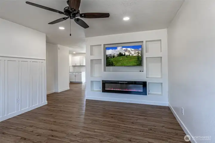 From the main entry stepping into the living room.  Nice wainscotting accent wall on the left.  Flat screen TV stays with home, electric remote controlled fireplace & cool art niches.