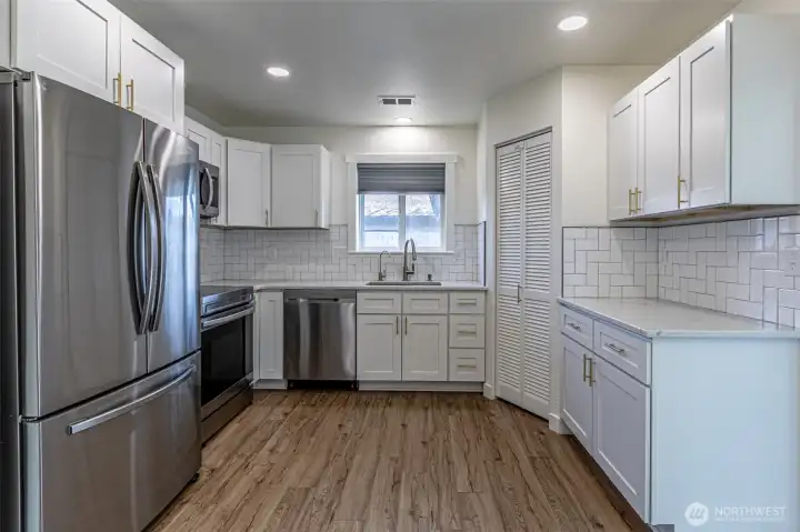 Newer kitchen with quartz counter, tile backsplash & full appliance package that stays with the home.  Corner pantry with shelves behind bifold doors.