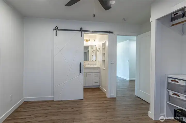Second view of the primary suite with barn door to the private bathroom.