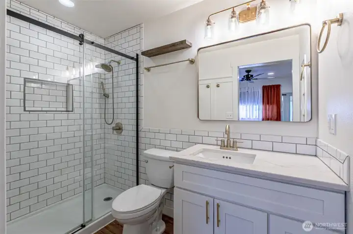 Great use of the tile & space. Oversized vanity & landscape mirror look great.  Tiled shower up to the ceiling with built in niche.