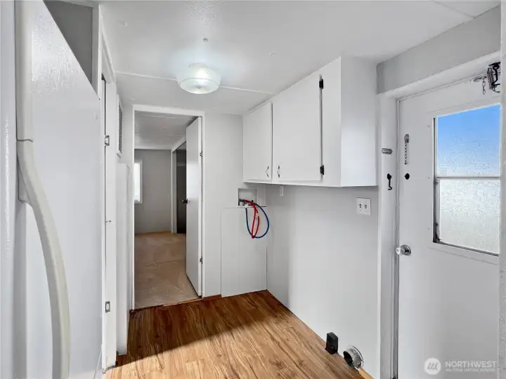 Laundry room in the hall with cabinets and exterior door.