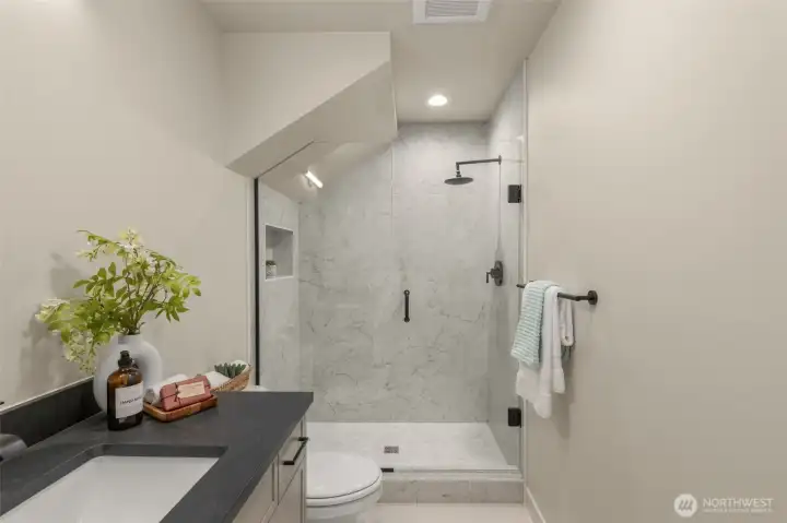 Neutral tile, sleek hardware, and excellent lighting create a spa-like retreat.