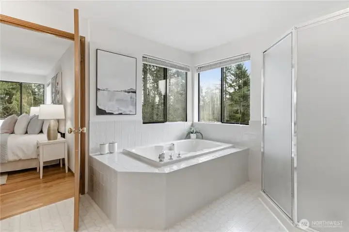 The primary bath features a corner soaking tub and separate shower, creating a serene, spa-like retreat. The wide tub ledge is ideal for candles, books, or a relaxing beverage—perfect for unwinding at home.