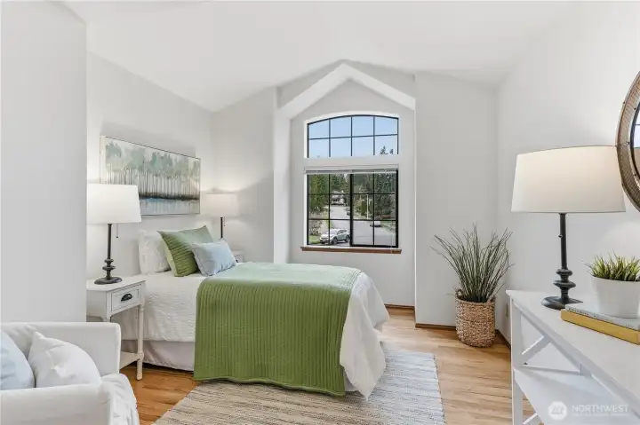 Bright front bedroom with striking cathedral ceilings and windows, offering western-facing light and an airy, open feel.