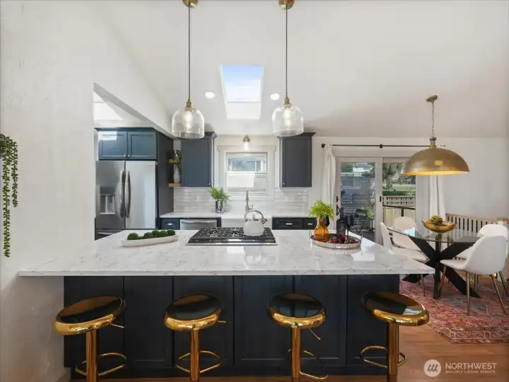 Showcasing Quartz countertops, custom cabinetry, oversized fireclay farmhouse sink, subway tile backsplash, stainless steel appliances including gas range and thoughtfully new statement pendants over kitchen island and added sconce lighting over both windows in the kitchen.