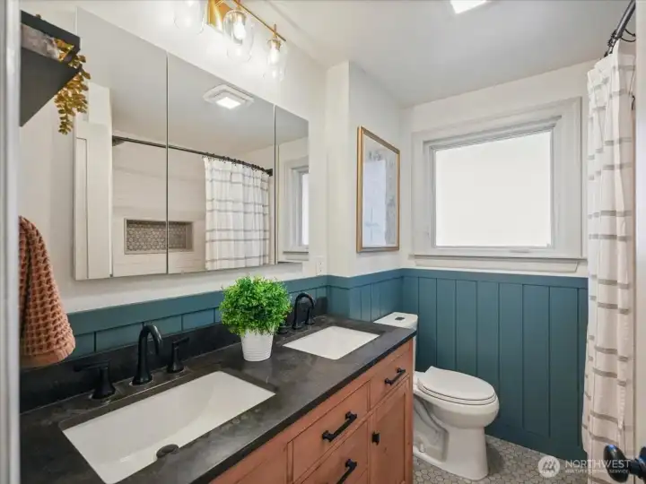 Remodeled full bath in 2022 includes new tile flooring, vanity with dual sinks, tiled tub/shower combo, toilet, lighting and mirror.