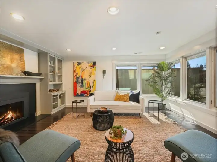 Inviting lower-level living space with stunning laminate flooring, a warm gas fireplace, and elegant custom built-ins—perfect for relaxing or entertaining.”