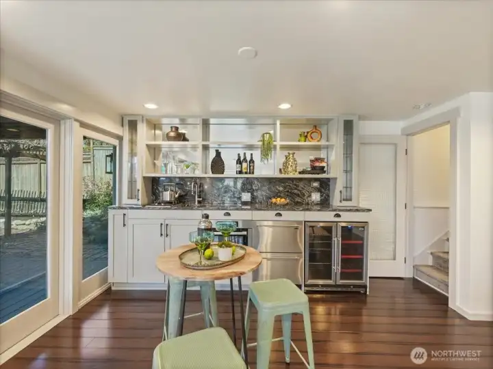Lower level kitchenette has beautifully appointed granite counters, custom cabinetry, open shelving  and wine fridge that provide both style and functionality.