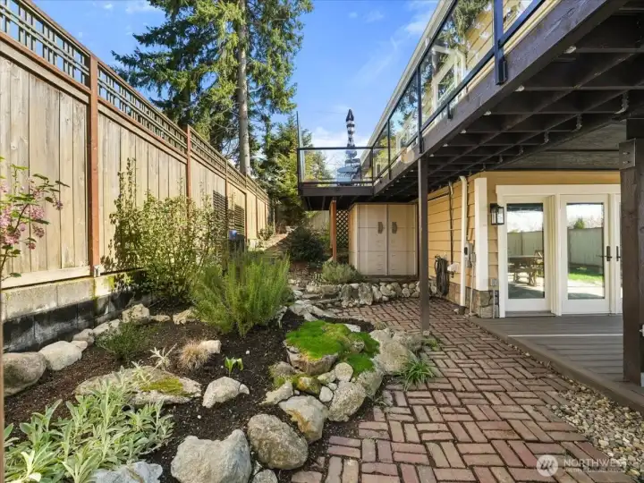Beautifully landscaped with various easy to care for plants. This walkway leads to another entertainment space which opens to a built-in firepit.