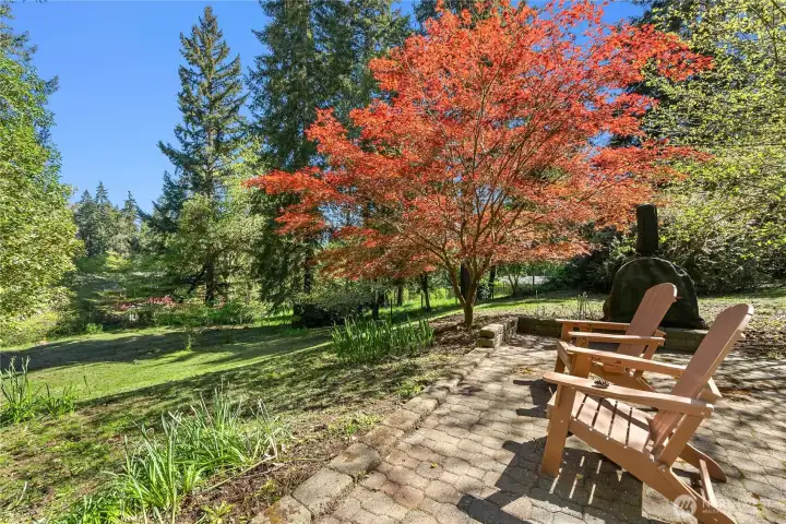 Outside, a stone walkway leads to a firepit, smoker, and lovely area to relax and enjoy the birdsong.