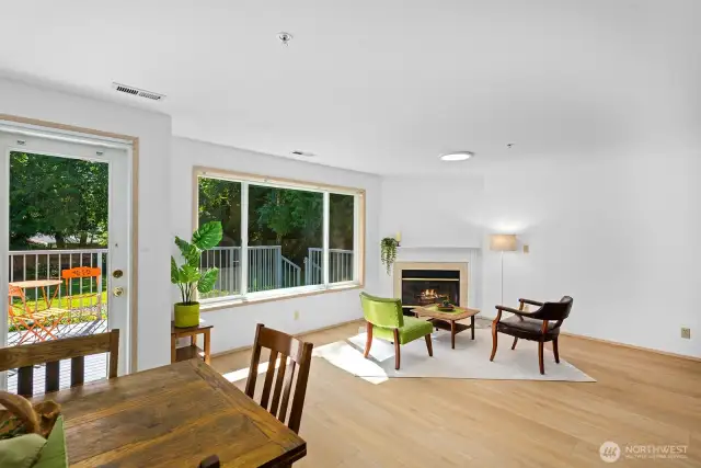 Large open living and dining area filled with light, picture windows, gas fire place and open to balcony and shared fenced in yard